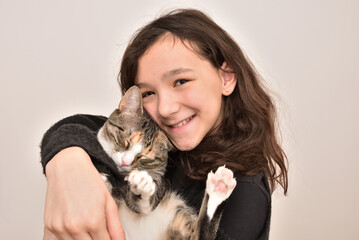 Obraz premium Smiling young girl holding her cat. Friendship of child and animal. Keeping pets at home, care and love of animals concept. 