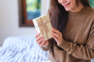 Closeup image of a woman in sweater holding a present box at home