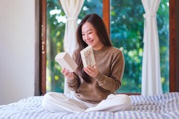 Portrait image of a happy woman receiving and opening a present box at home