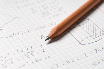 Fototapeta premium Copybook with handwritten maths formulas and pencil as background, closeup