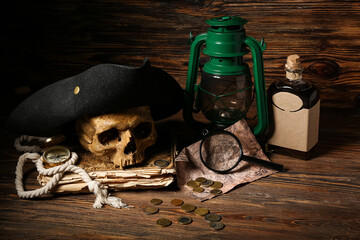 Human skull with pirate hat, old manuscripts, oil lamp and travel equipment on brown wooden background © Pixel-Shot