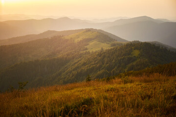 Mountains and hills under a sunset sky with warm light spreading across the landscape in summer. Summer Hiking in Carpathian Mountains. Ukraine