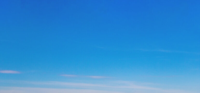 Clear blue gradient sky background with soft transition from deep to light tones and scattered wispy clouds, offering a calm and minimalist visual atmosphere.