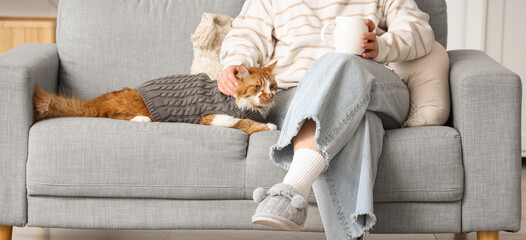 Woman with coffee and cute cat relaxing on sofa at home