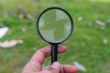 Hand holding magnifying glass in outdoor	