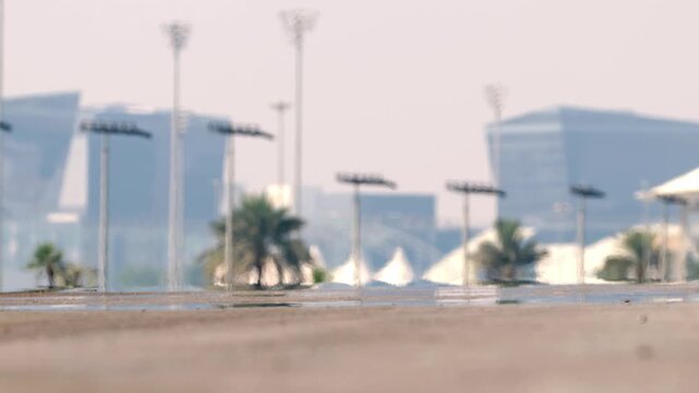 Mirage effect at empty desert road with skyscrapers in background, shimmering air above hot asphalt