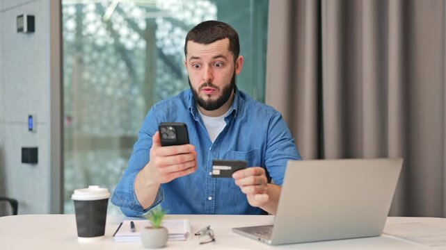 Individual reacts with surprised and concerned expression while attempting online payment using credit card smartphone. Shock encountering an unforeseen transaction issue during virtual purchase.