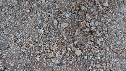 Above view of natural ground texture consisting of dry earth. Surface features a mix of tan brown and grey tones providing a realistic background for construction.