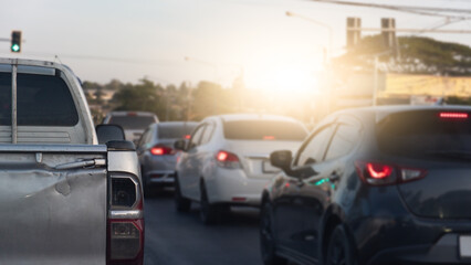 Rear side of pickup car driving on the road. Pickup of car tail lights were also dented and damaged. Many car turn on brake light for pass from traffic light green color in the city.