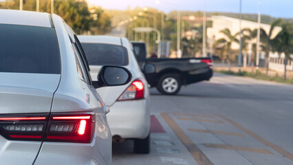 Rear view of white car with LED turn signal indicator. Luxury vehicle exterior part with reflection and blurred road background. Queuing up with a pickup truck crossing the intersection.