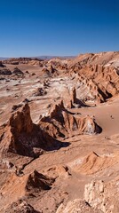 Arid desert valley features dramatic rock formations under clear blue sky