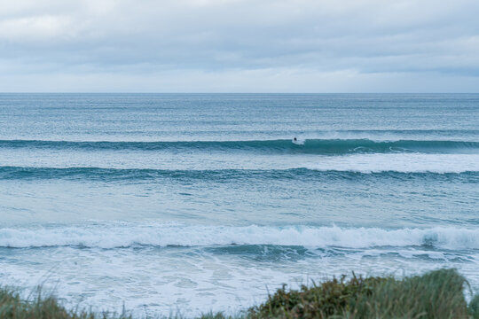Surfer riding ocean wave with overcast sky