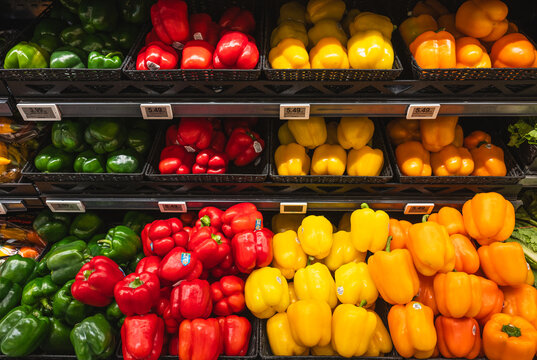 Close up of variety of bell peppers on a shelf in the grocery store.