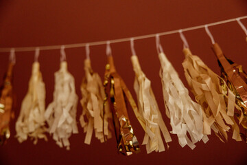 Obraz premium Gold and cream tassel garland hanging against a red wall.