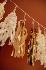 Obraz premium Gold and cream tassel garland hanging against a red wall.