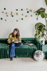 Obraz premium Woman sits on velvet covered couch writing in notebook