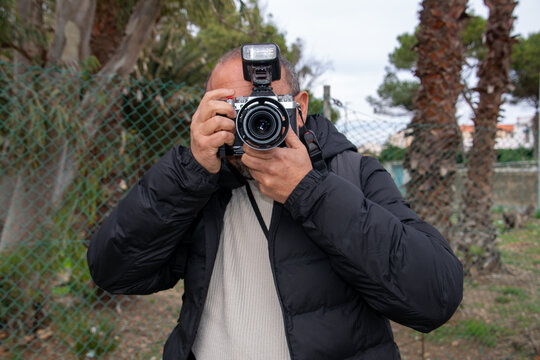 Man with a camera to his face, ready to take a photograph
