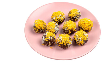 Pink plate holds chocolate truffles with orange & white toppings, isolated on black