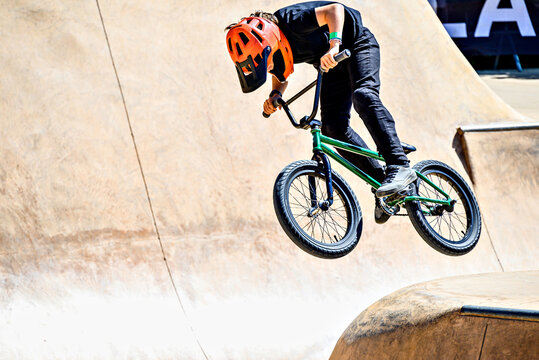 A young man practicing BMX and performing tricks at the skatepark.
