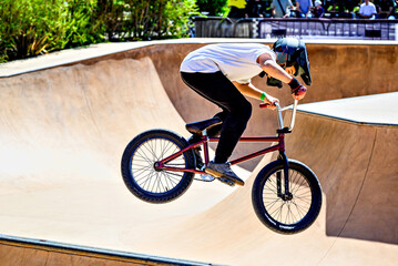 Obraz premium A young man practicing BMX and performing tricks at the skatepark.
