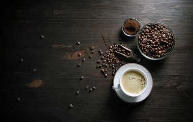 Delicious fresh coffee. Coffee cup, roasted coffee beans and ground powder on wooden surface. Flat lay.