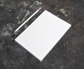 Copybook and pencil on concrete surface. Blank objects for placing your design.