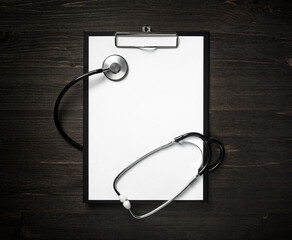 Medical still life. Blank medical clipboard and stethoscope on wooden surface. Flat lay.