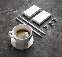 Photo of coffee cup and blank stationery set on concrete surface.
