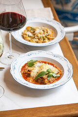 Traditional italian lasagna with tomato sauce cheese and basil served on plate with glass of red wine