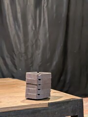 a pile of gray ashtrays arranged like Lego. placed on the edge of the table © Leny