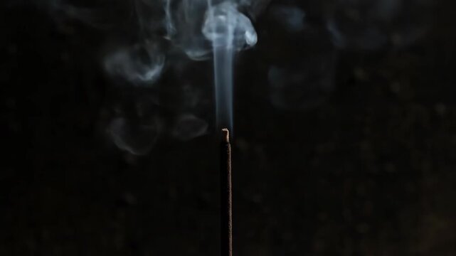 A single sparkler burns brightly against a dark background Delicate smoke rises and curls upward creating a magical fleeting moment