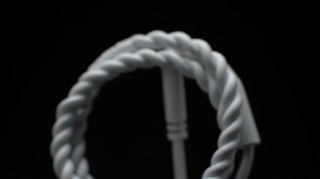 A thick white coiled rope rests against a dark background The rope appears heavy and strong perhaps for nautical or industrial use highlighting its texture and form