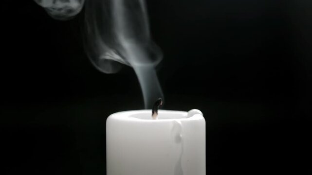 Extinguished candle with rising smoke on a dark background viewed from a close-up perspective, capturing the serene ambiance of a peaceful environment with wax, wick, smoke, and stillness.