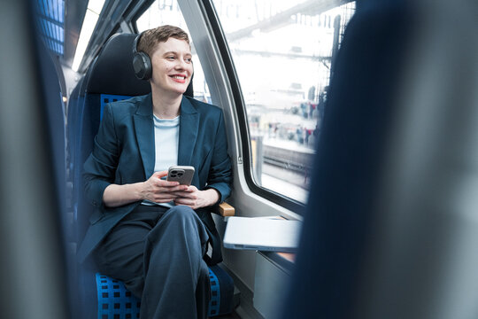 Businesswoman listening to music and using mobile on train journey