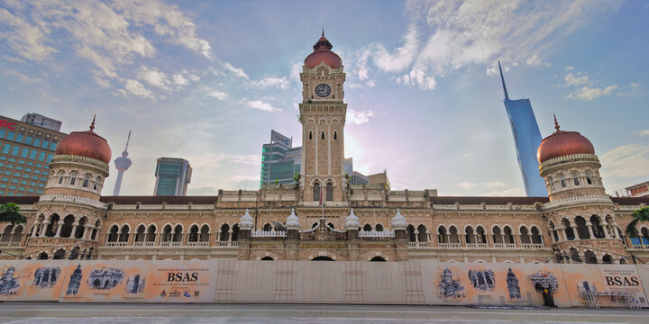 Kuala Lumpur, Malaysia - February 17, 2025: Sultan Abdul Samad Building with its iconic clock tower, copper domes, and Merdeka 118 under a cloudy sky