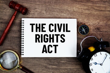 The Civil Rights Act message written on notepad with alarm clock, wood gavel and magnifying glass...