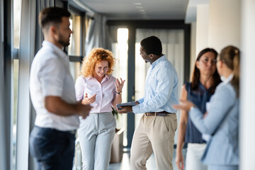 Business professionals networking and discussing ideas in modern office hallway