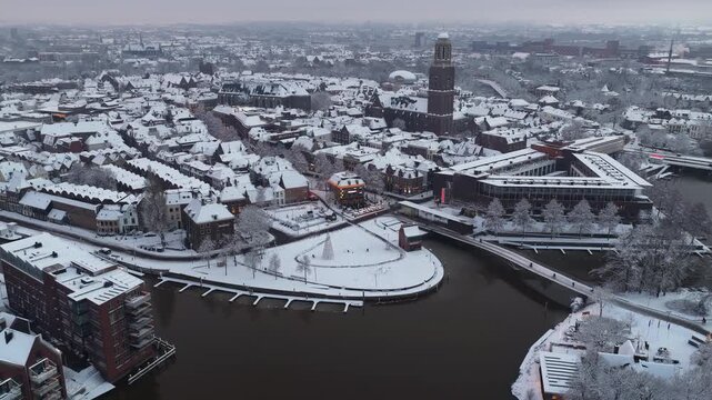 Zwolle Peperbus church tower rising up over the snow covered rooftops in the downtown district aerial drone view during a cold winter overcast morning.