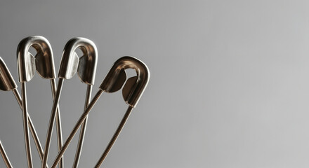 Safety pins in close-up minimal style on gray background symbolizing utility
