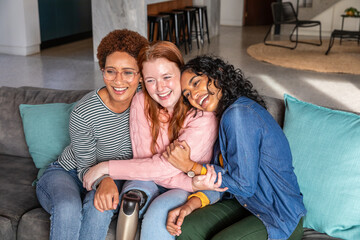 Diverse female friends chatting on gray sofa in living room featuring visible prosthetic leg