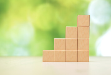 Stacked Wooden Blocks on Light Background With Blurred Greenery During Daylight