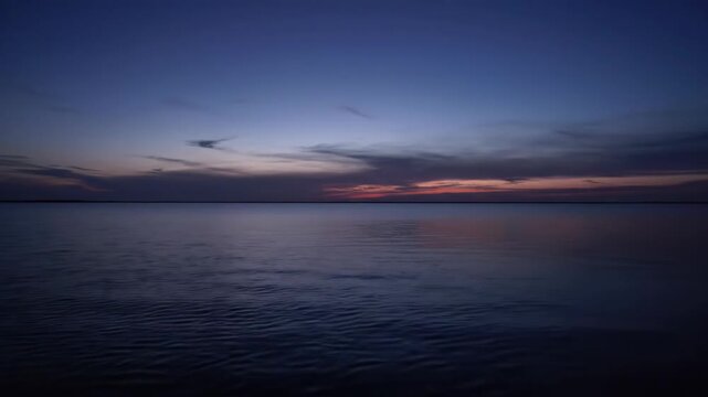 A serene twilight scene over a calm ocean horizon A lone airplane flies against the deep blue and purple gradient sky signaling the end of the day