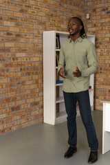 African american man gesturing and presenting at industrial office with brick wall, bookshelf