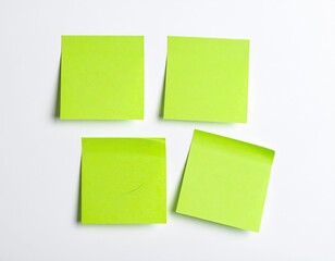 Fototapeta premium Four green sticky notes on a plain white background