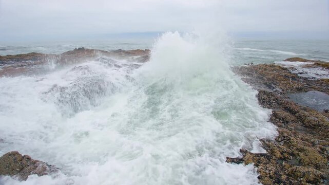 Footage of Thor's Well, also known as the Drainpipe of the Pacific, a collapsed sea cave that creates the illusion of a bottomless pit at Cape Perpetua Scenic Area in Oregon during high tide with cras