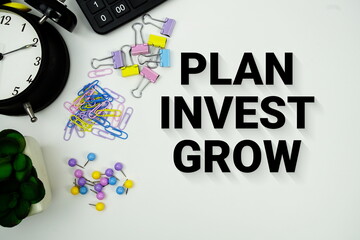 Plan Invest Grow message with calculator, alarm clcok and Stationery on white background