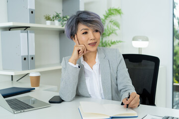 Obraz premium Confident Mature Businesswoman in Modern Office Using Technology with Positive Energy and Professional Presence.