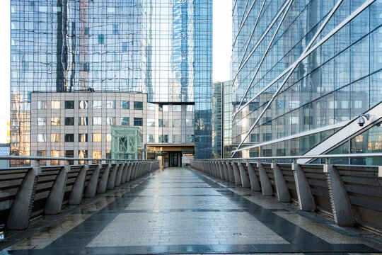 Modern architecture walkway bridge urban office glass Paris La Defense perspective through an empty passage with railings and city depth ahead