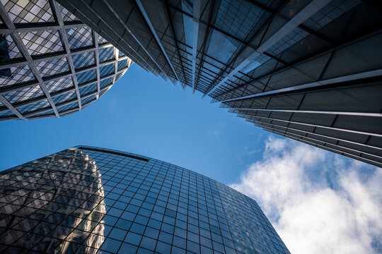 Curved architecture skyscraper glass reflection Paris La Defense office modern angle looking up with dramatic sky and converging tower lines