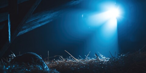Mystical light beam illuminating dark barn interior with straw and shadows